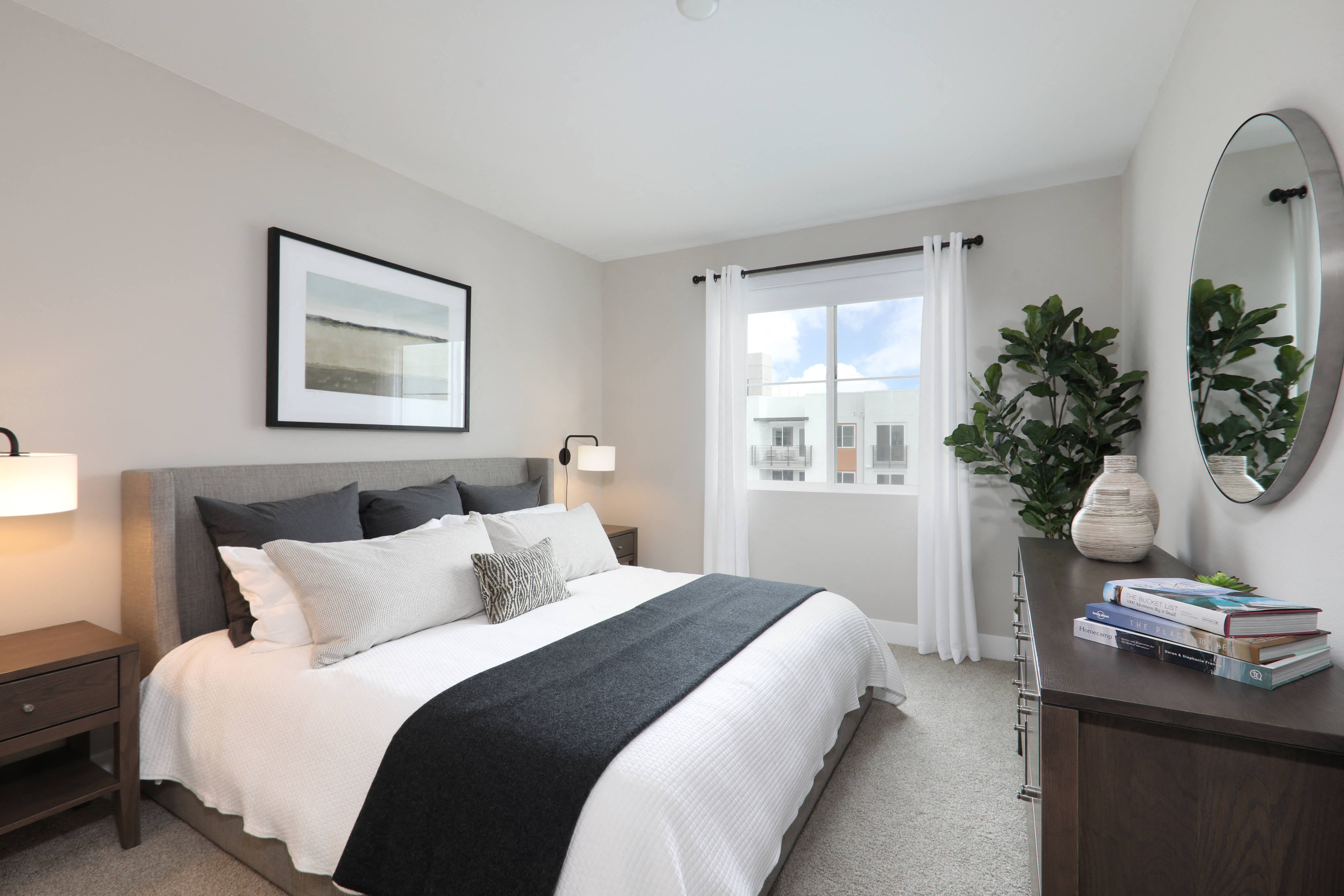Cozy bedroom featuring a comfortable bed, dresser, and a large window for natural light.
